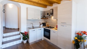 Una cocina moderna con armarios blancos, horno empotrado y techo de madera.