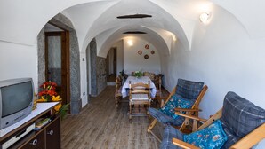 Un couloir étroit avec un lit en bois, une télévision et un coin salon agrémenté d’un coussin bleu.