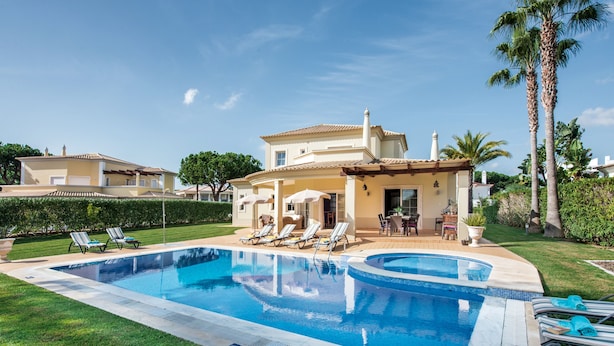 Un área junto a la piscina con piscina, sillas de descanso y un patio con mobiliario exterior.
