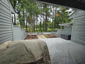 Une terrasse couverte avec une pergola, un jardin clos et une vue sur une zone boisée.