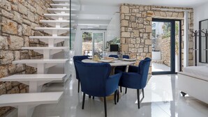 A modern interior with a stone wall, a staircase, a dining area with blue chairs, and a bed. - Dion Villa Zakynthos Greece One Bedroom Villa With Private Pool No01 (Zakynthos)