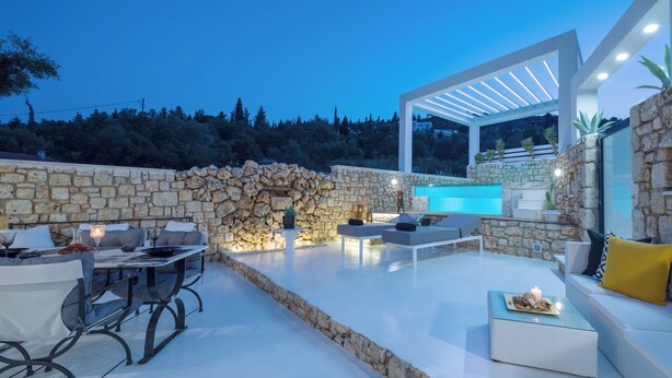 A modern outdoor patio with stone walls, a pool, and seating areas. - Dion Villa Zakynthos Greece One Bedroom Villa With Private Pool No01 (Zakynthos)