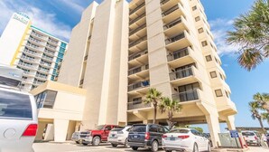 A multi-story hotel with balconies, a parking lot, and palm trees. - Shoreham Towers I - C3 (North Myrtle Beach)