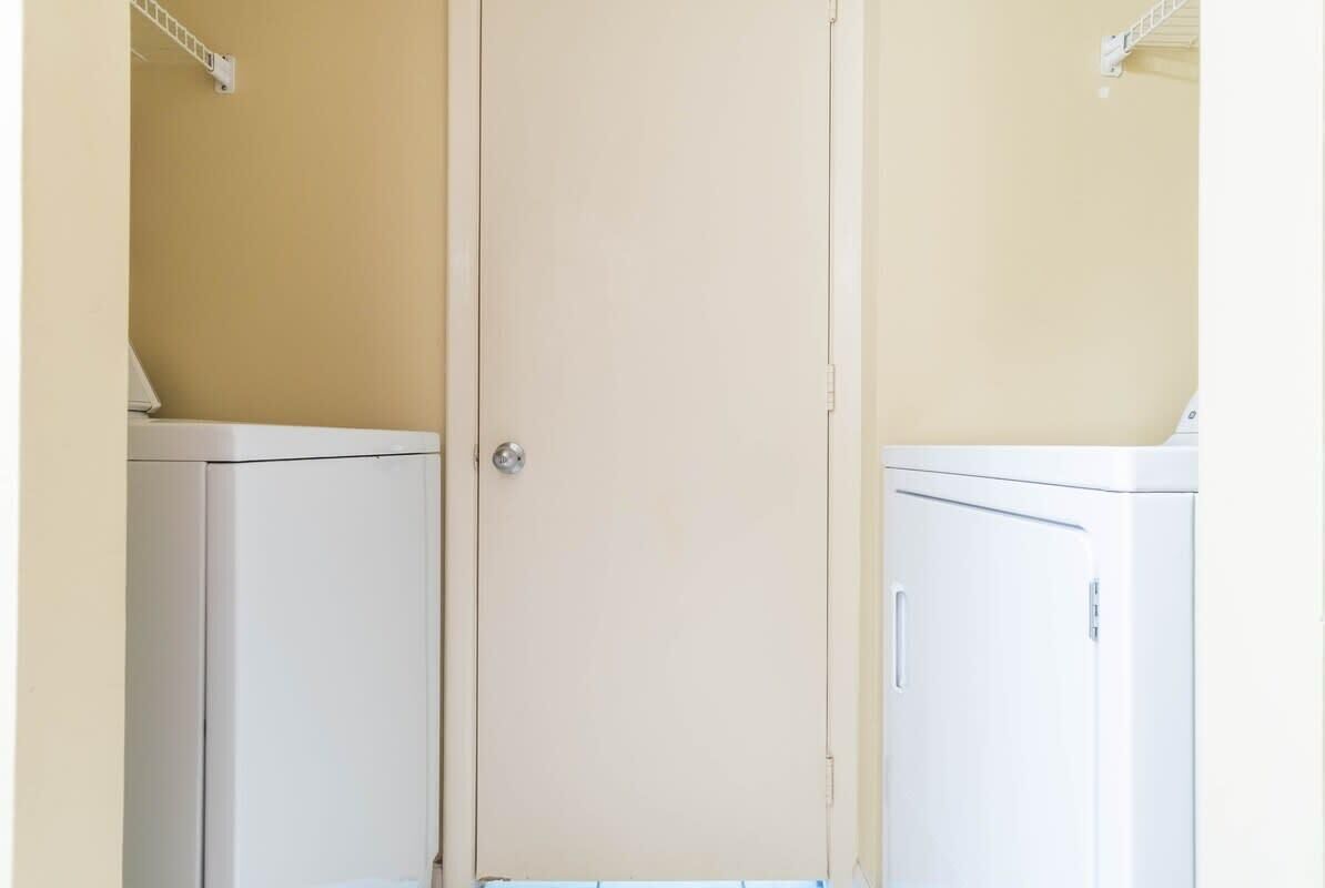 Una habitación con dos armarios blancos frente a una pared amarilla.