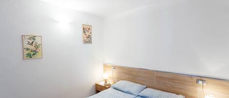 Un dormitori amb llit, dues taules de nit i decoració mural.