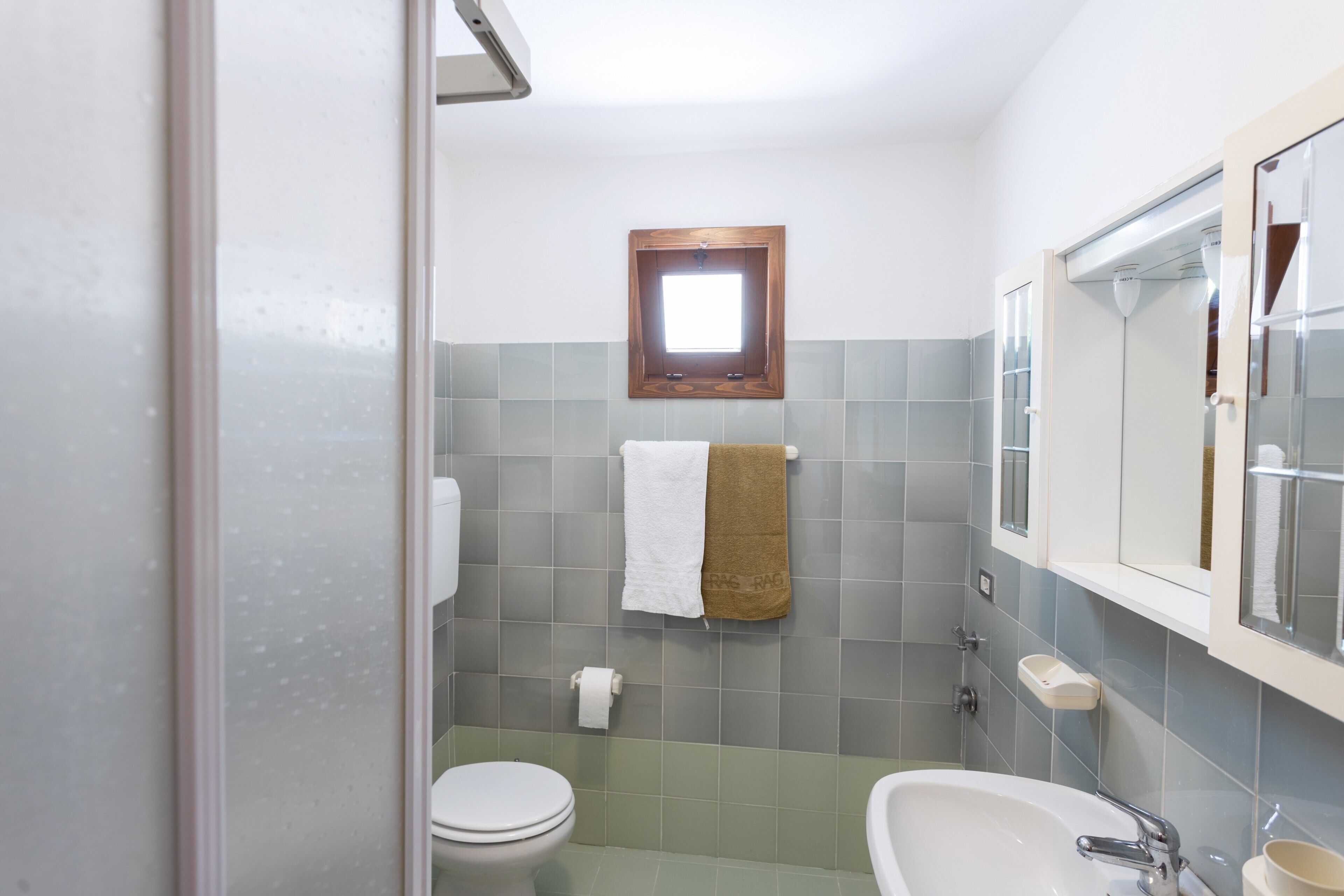 Een badkamer met toilet, wastafel en spiegel.