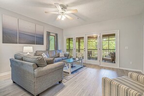 Un salon spacieux avec un canapé gris, une table basse et un ventilateur de plafond.