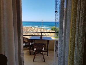 Un balcón con mesa y sillas, con vistas a la costa y el mar, con edificios a lo lejos.