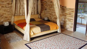 Una cama con dosel, colcha, cabecero de madera y un fondo de pared de piedra.