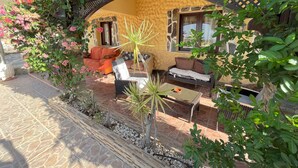 Un espacio exterior con mobiliario de mimbre, suelo de baldosas de piedra y un arco decorativo.