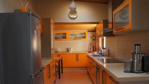 Una cocina moderna con armarios de madera, un refrigerador de acero inoxidable, una cafetera y una licuadora sobre la encimera.