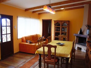 En hyggelig stue med et træspisebord, orange sofa og en pejs.