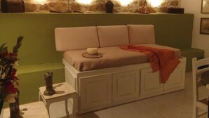 A cozy room with a sofa, a small table with a lamp, and a decorative vase. - "aristidis Stone House" (Corfu)