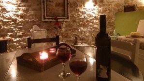 A stone-walled room with a table set for two, featuring a bottle of wine and two glasses. - "aristidis Stone House" (Corfu)