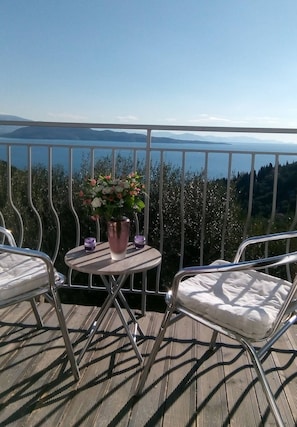 Un balcon avec une table, des chaises et un pot de fleurs.
