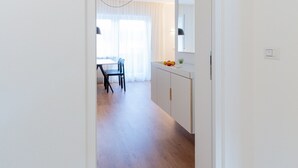 A hallway leading to a dining area with a table and chairs, a kitchen area with cabinets, and a number '2' on the wall. - Modern "Hus Apartment - Nr. 2" with Balcony, Garden & Wi-Fi (Olang)