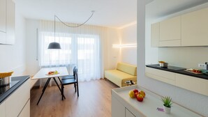 A modern kitchen with a dining area, a sofa, and a small table with fruit. - Modern "Hus Apartment - Nr. 2" with Balcony, Garden & Wi-Fi (Olang)
