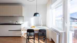 A modern kitchen with a dining area, a black pendant light, and a view of a mountain through a large window. - Modern "Hus Apartment - Nr. 2" with Balcony, Garden & Wi-Fi (Olang)