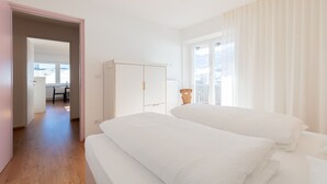 A bedroom with two beds, a wardrobe, and a view of the outdoors. - Modern "Hus Apartment - Nr. 5" with Balcony, Garden & Wi-Fi (Olang)