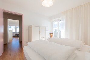 Une chambre avec deux lits, une armoire et une vue sur l’extérieur.