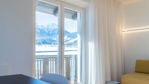 A hotel room with a balcony, a bed, a chair, and a table. - Modern "Hus Apartment - Nr. 5" with Balcony, Garden & Wi-Fi (Olang)