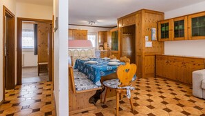 Een compacte keuken met houten kastjes en een eethoek met een tafel voor twee.