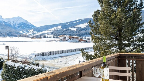 A balcony with a table and chairs, overlooking a snowy landscape and mountains. - Modern "Hus Apartment - Nr. 3" with Balcony, Garden & Wi-Fi (Olang)