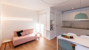 A modern apartment with a sofa, kitchenette, and a dining area. - Modern "Hus Apartment - Nr. 3" with Balcony, Garden & Wi-Fi (Olang)