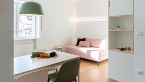 A modern living space with a dining area, a sofa, and a built-in shelving unit. - Modern "Hus Apartment - Nr. 3" with Balcony, Garden & Wi-Fi (Olang)