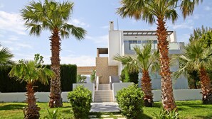 A modern house with a paved entrance, surrounded by palm trees and a well-maintained lawn. - Xenos Villa 1 With Private Swimming Pool Near The Sea (Kos)