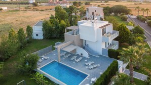 A modern residential property with a swimming pool, multiple lounge chairs, and a well-maintained garden. - Xenos Villa 1 With Private Swimming Pool Near The Sea (Kos)