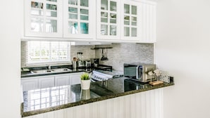 A modern kitchen with white cabinetry, a granite countertop, and a built-in stove. - White Sands Beach (Punta Cana)