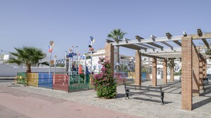 Un espace extérieur abrité, doté d’un banc, d’une colonne en briques et d’un palmier.