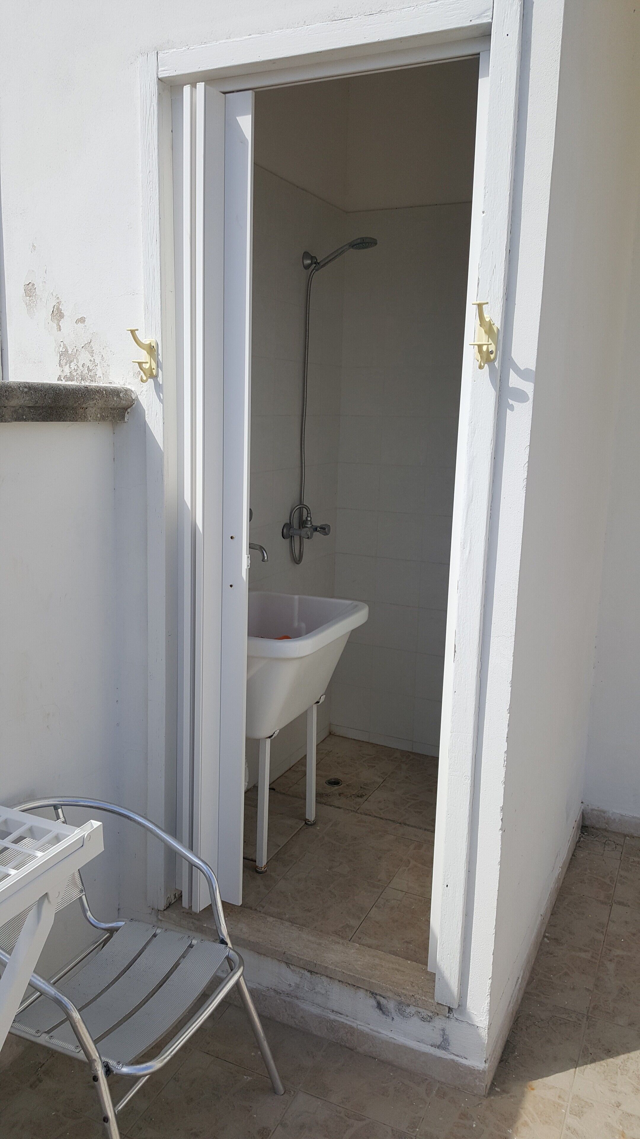 Un bagno piccolo e separato con un lavandino e una doccia bianchi.