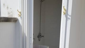 Un bagno piccolo e separato con un lavandino e una doccia bianchi.