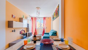 A dining area with a table set for four, a bottle of wine, and a colorful abstract painting on the wall. - Seaside Holiday in Otranto - Virginia Deluxe (Otranto)