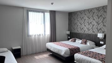 Habitación de hotel con dos camas, un ventanal con cortinas translúcidas, un papel tapiz estampado y una cámara de seguridad instalada en el techo.