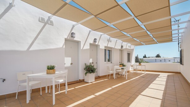 A spacious outdoor patio with white furniture, potted plants, and a clear view of the sky. - Modern studio apartment - La Higuera 2 (Cadiz)