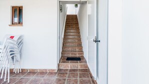A staircase leading to a landing with a door on the right, a small window on the left, and a black doormat at the bottom. - Modern studio apartment - La Higuera 2 (Cadiz)