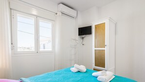 A bedroom with a bed, a wardrobe, a TV, and an air conditioning unit. - Modern studio apartment - La Higuera 2 (Cadiz)