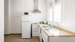 A compact kitchen with a refrigerator, microwave, sink, and built-in oven. - Modern studio apartment - La Higuera 2 (Cadiz)