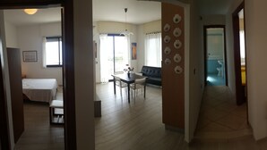 Un corridoio con zona pranzo, un letto e una parete decorata con piatti e opere d'arte.