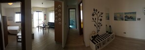 Een gang met een eetgedeelte, een bed en een wand met decoratieve borden en kunstwerken.