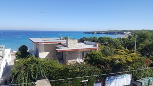 Un edificio costiero con facciata in pietra, tetto piatto e vista sul mare.