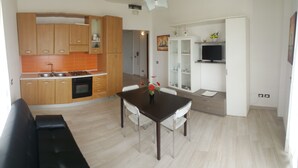 Una cucina moderna con mobili in legno, un tavolo da pranzo con sedie e un televisore in zona living.