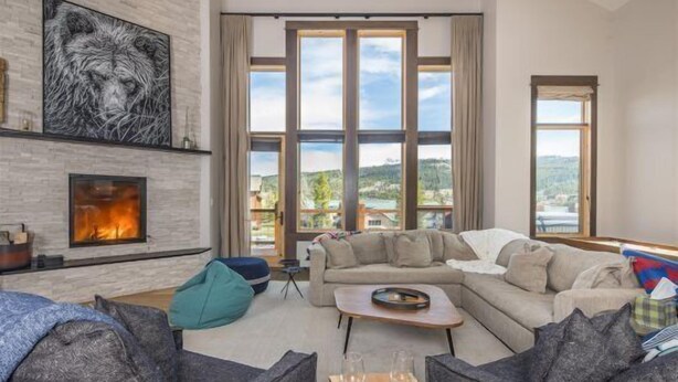 A modern living room with a fireplace, large windows, and a view of a mountainous landscape.