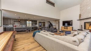 A spacious living area with a large sofa, a wooden coffee table, and a television mounted on the wall.