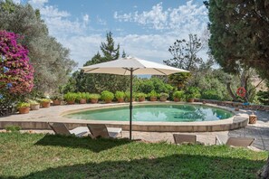 A swimming pool with a surrounding patio area, including a lounge chair and a sun umbrella.