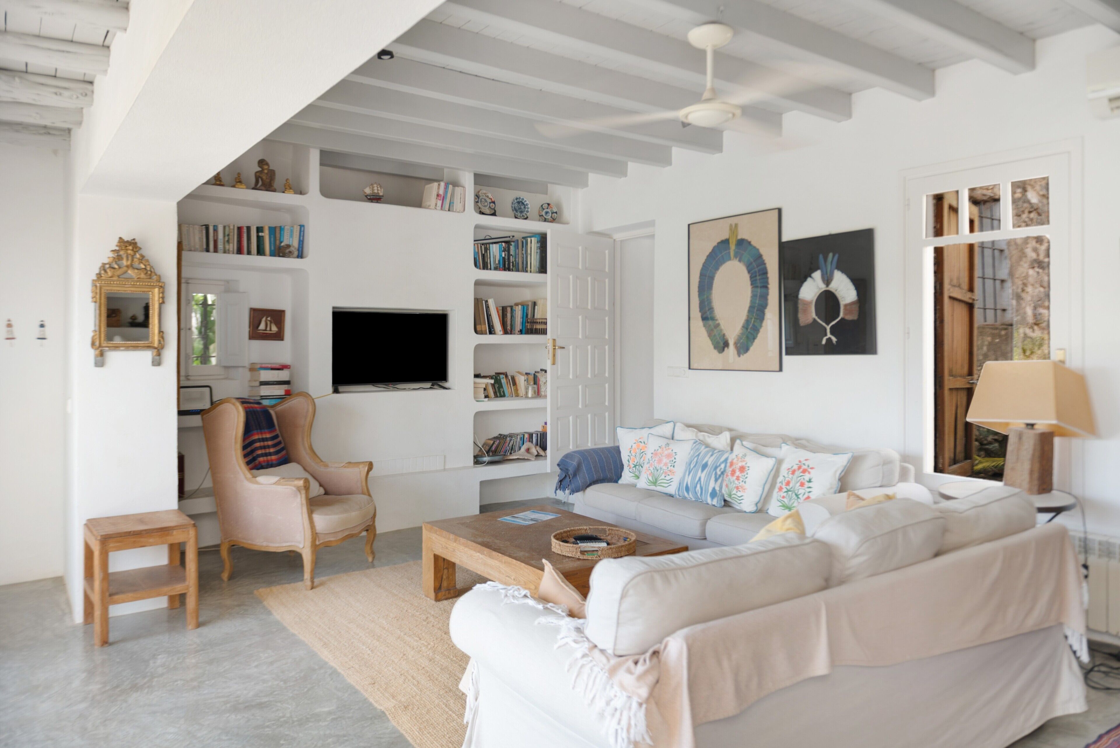 Una sala de estar con sofá, sillón, mesa de centro y estanterías.