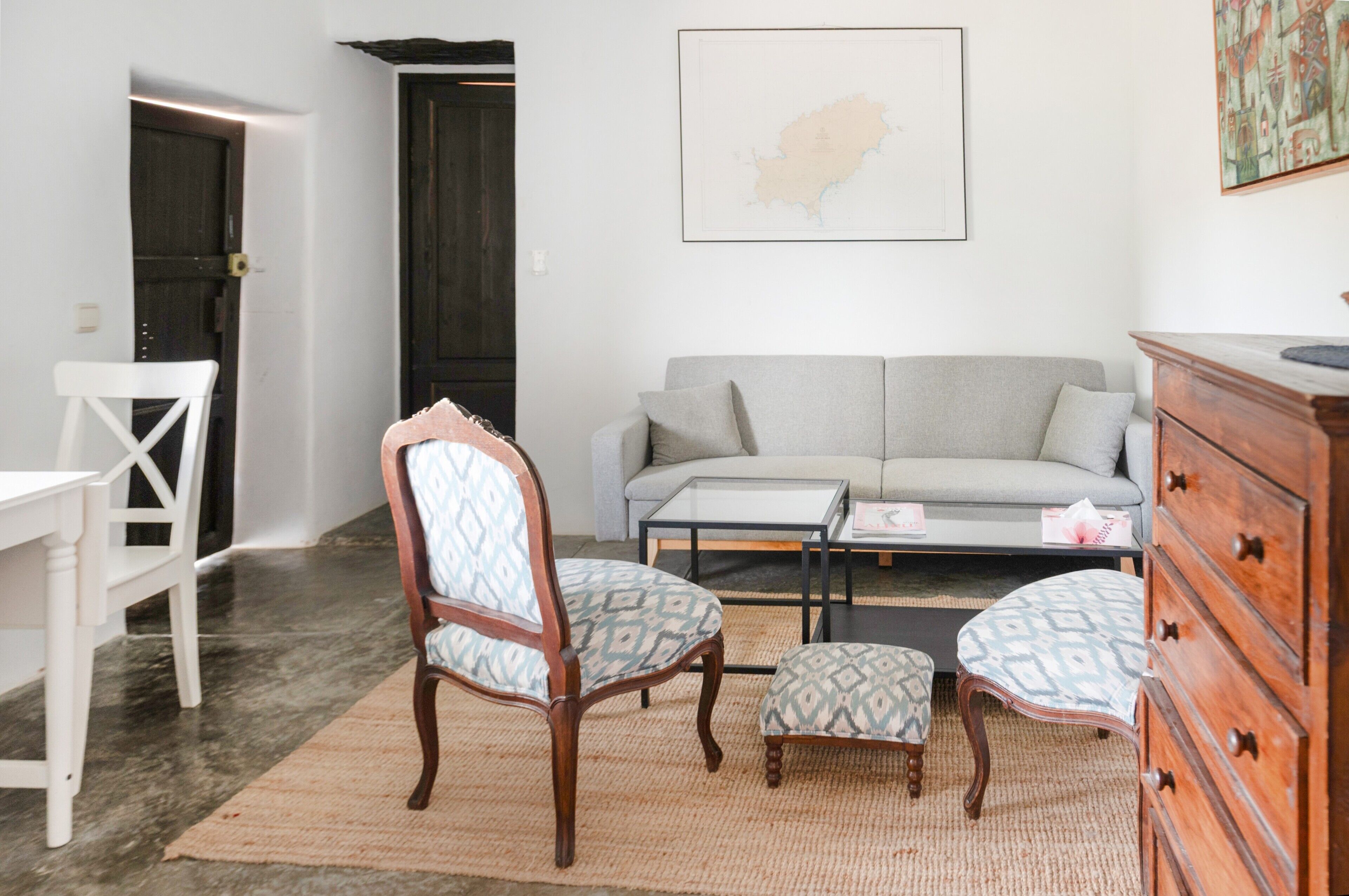 Un salon comprenant un canapé, deux fauteuils, une table basse et une commode en bois.